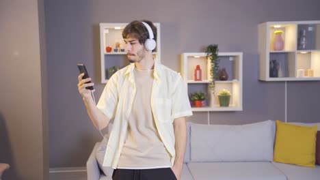 Young-man-listening-to-music-with-headphones-on-his-smartphone.